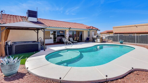 A backyard with a swimming pool, a hot tub, and a covered patio area with lounge chairs. - Cozy Lake Havasu City Home - Pool and Hot Tub (Lake Havasu City)
