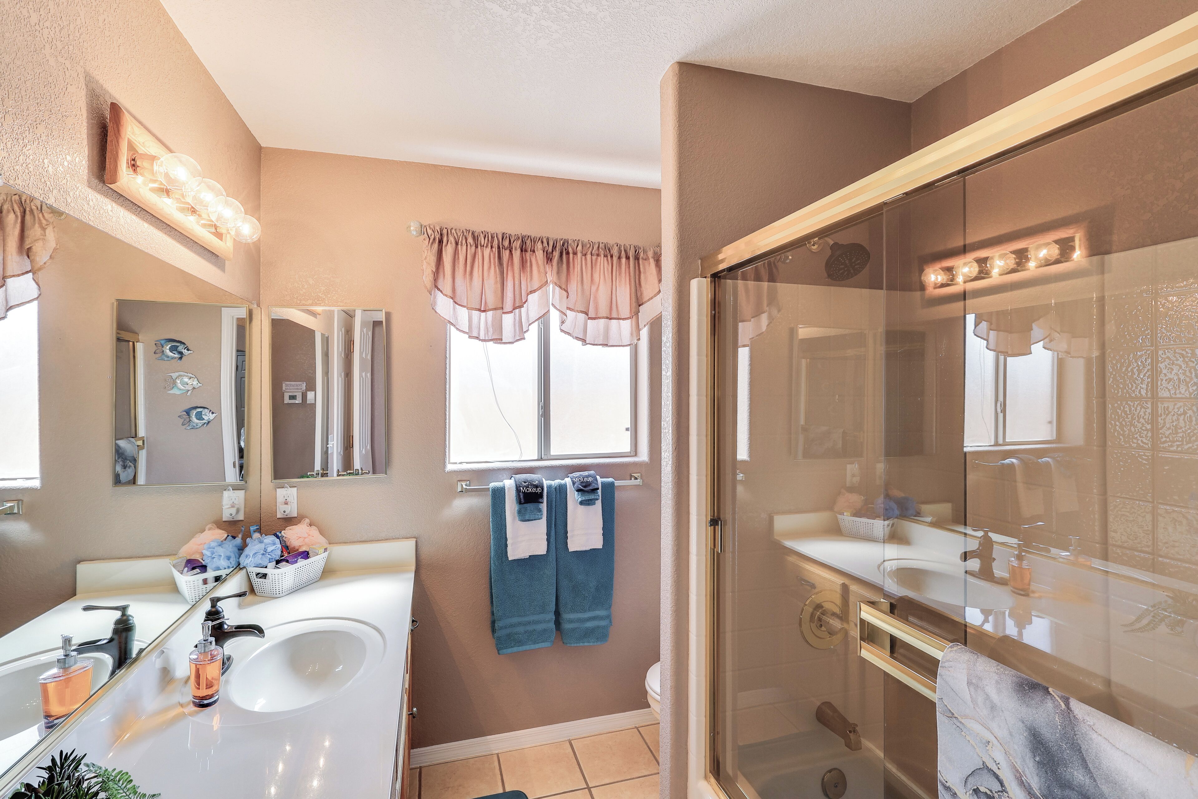 Un baño con dos lavamanos, cabina de ducha de vidrio y un espejo de tocador.