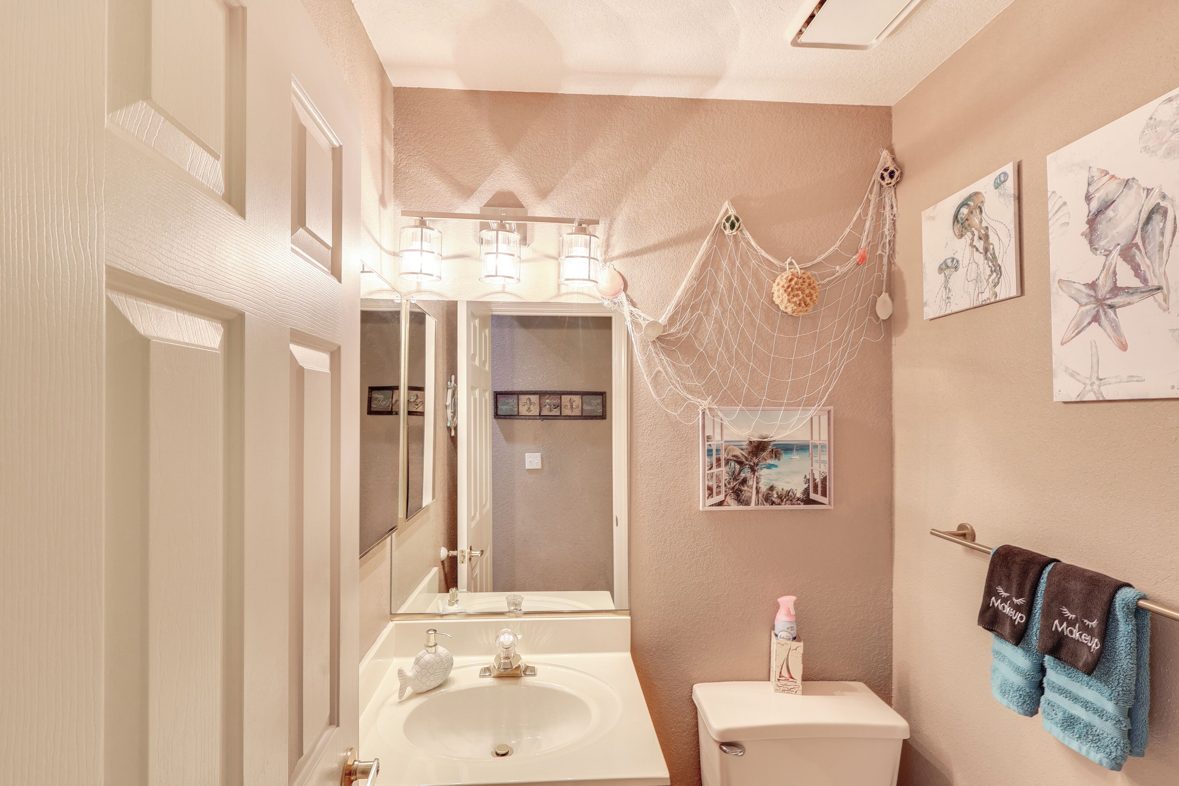 Baño con lavamanos, espejo, inodoro y una red decorativa.
