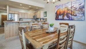 A spacious kitchen with wooden cabinets, a central island, and a dining area with rustic chairs. - Walk to Ski Lift: Breck Condo w/ Hot Tub (Breckenridge)