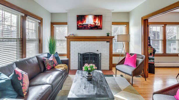 A living room with a fireplace, a sofa, a coffee table, and a TV mounted above the fireplace. - Spacious Detroit Lakes Home: Walk to Downtown! (Detroit Lakes)