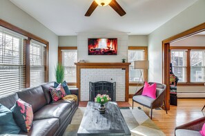 A living room with a fireplace, a sofa, a coffee table, and a TV mounted above the fireplace.