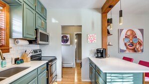 A modern kitchen with teal cabinets, a microwave, and a coffee maker. - Spacious Detroit Lakes Home: Walk to Downtown! (Detroit Lakes)