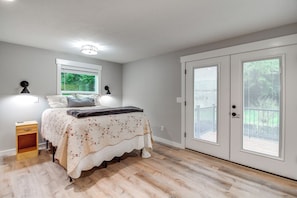 A bedroom with a bed, bedside lamps, a window, and a sliding door to a balcony. - 3 Mi to Reedsport: Home w/ Umpqua River Views (Reedsport)