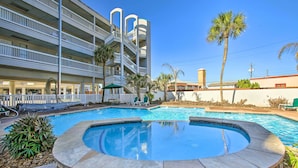 A hotel with a swimming pool, multiple balconies, and palm trees. - Galveston Condo w/ Beach Access Near Moody Gardens (Galveston)