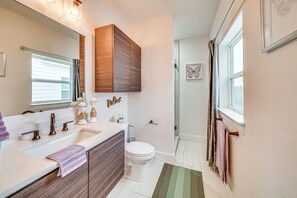 A modern bathroom with a large mirror, a vanity with a sink, and a toilet.