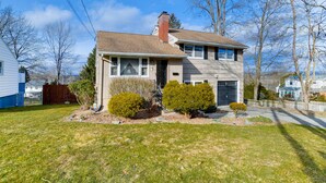 A two-story house with a front porch, a garage, and a well-maintained lawn.