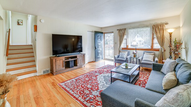 A living room with a TV, sofa, coffee table, and a red rug.