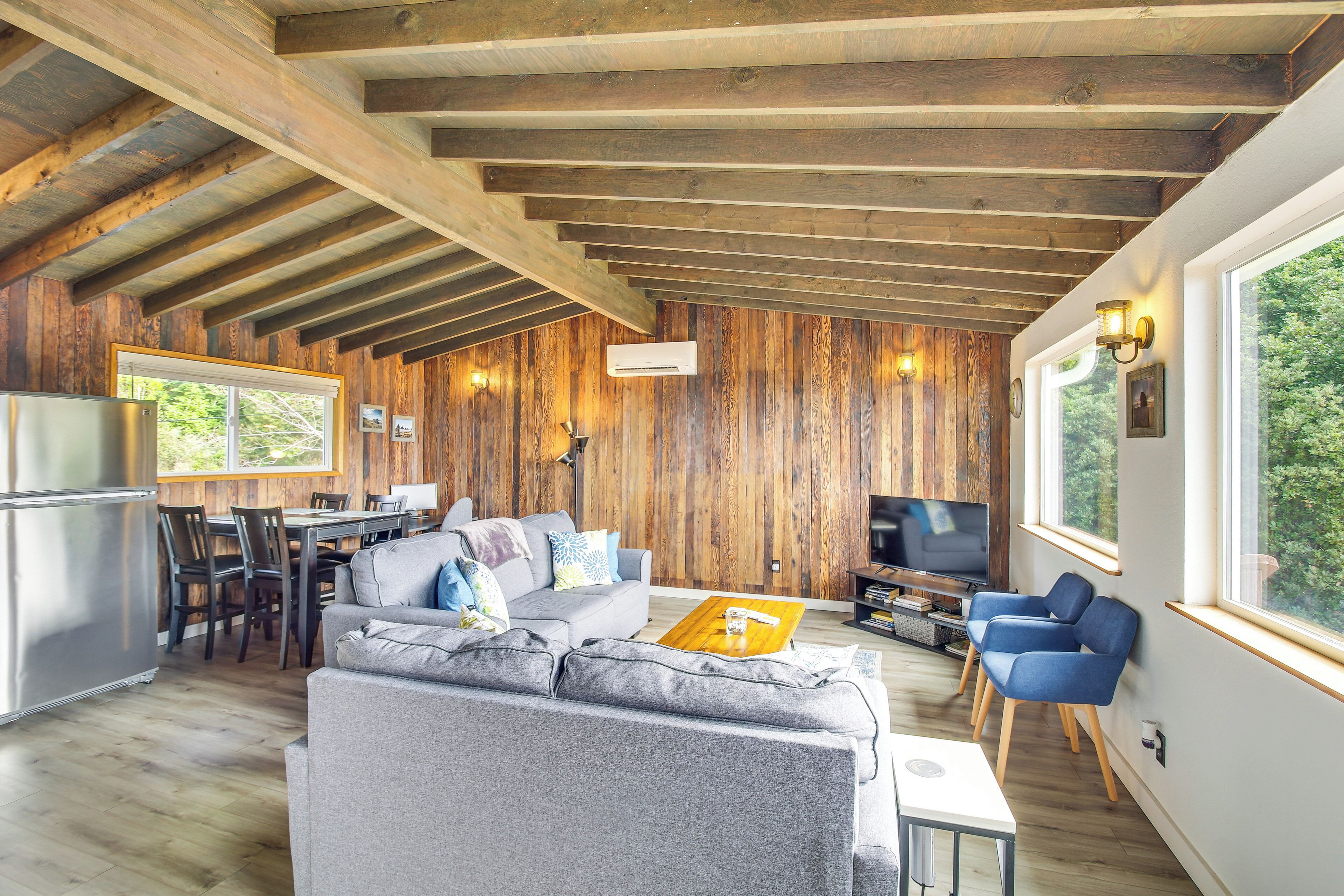 A spacious living area with a wooden ceiling, a gray sofa, a coffee table, and a TV.