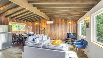 A spacious living area with a wooden ceiling, a gray sofa, a coffee table, and a TV.