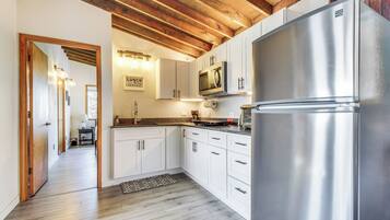 A modern kitchen with white cabinets, a stainless steel refrigerator, and a wooden ceiling.