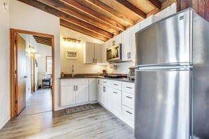Una cocina moderna con armarios blancos, un refrigerador de acero inoxidable y un techo de madera.