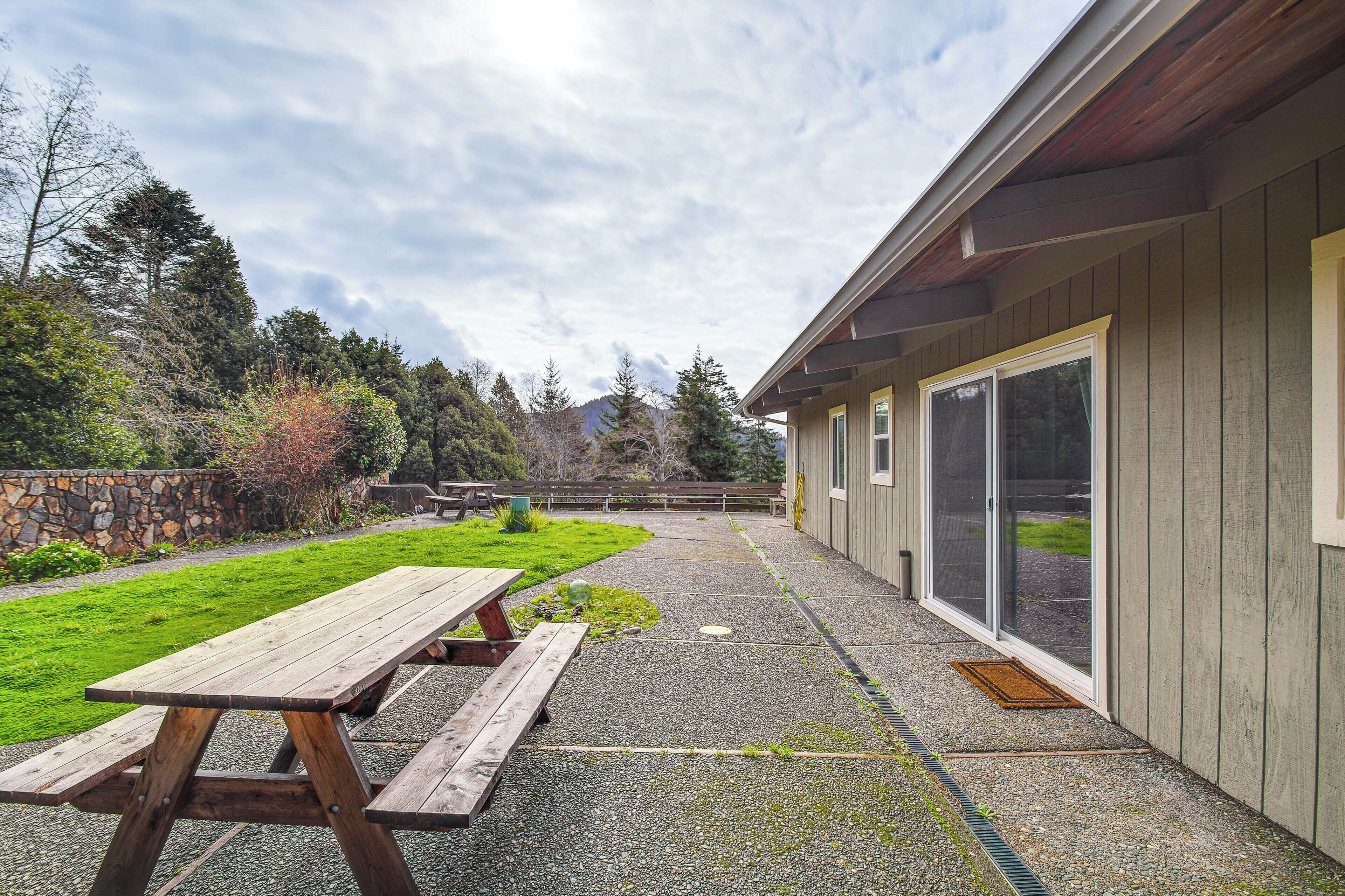A patio area with a wooden picnic table and a stone wall.