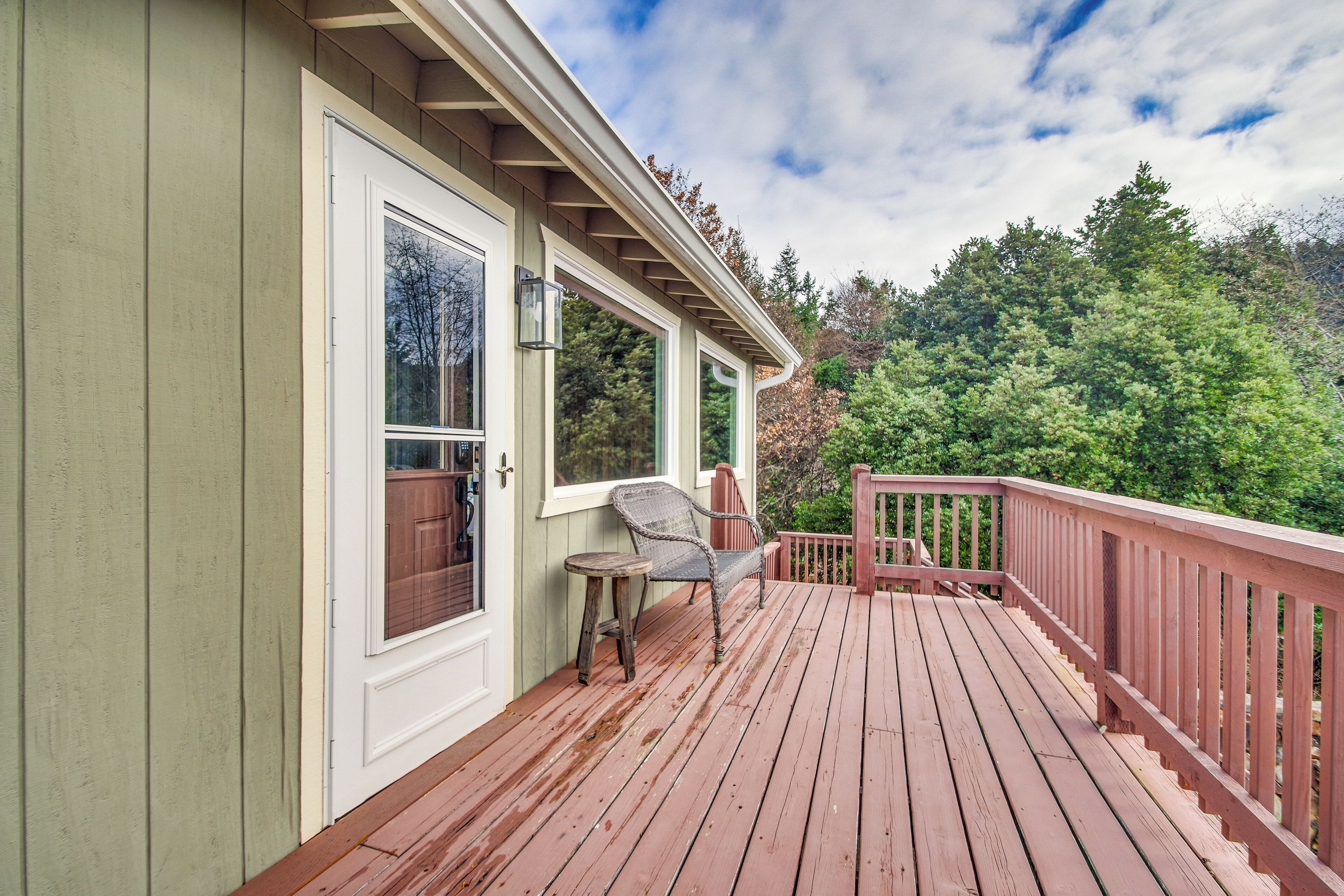 A wooden deck with a railing, a chair, and a table.