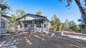 A two-story house with a covered porch, a fenced yard, and a driveway leading to a parked car. - Mtn Views + Playground: Family-friendly Pine Cabin (Pine)