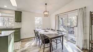 A dining area with a table, chairs, and a pendant light. There is a window with a view of the outdoors. - Mtn Views + Playground: Family-friendly Pine Cabin (Pine)
