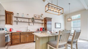 A kitchen with wooden cabinets, a granite countertop, and a central island with chairs. - Idyllic Lago Vista Home < 1 Mi to Lake Travis! (Leander)