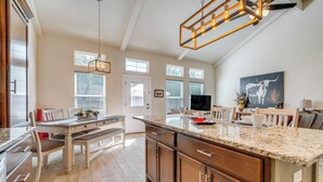 A spacious kitchen with a granite countertop, wooden cabinets, and a dining area with a bench. - Idyllic Lago Vista Home < 1 Mi to Lake Travis! (Leander)