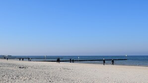 A wide sandy beach with a clear blue sky and calm sea.