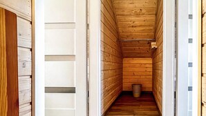 A narrow wooden hallway with a metal trash can at the end.