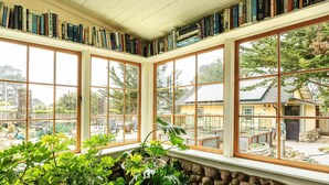 Ein Zimmer mit großen Fenstern, einer Steinwand und einem Bücherregal voller Bücher.
