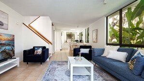 A modern living room with a sofa, a coffee table, and a TV.