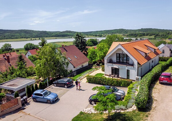 A residential area with houses, a lake, and a paved driveway. - Pilger Apartments (Tihany)