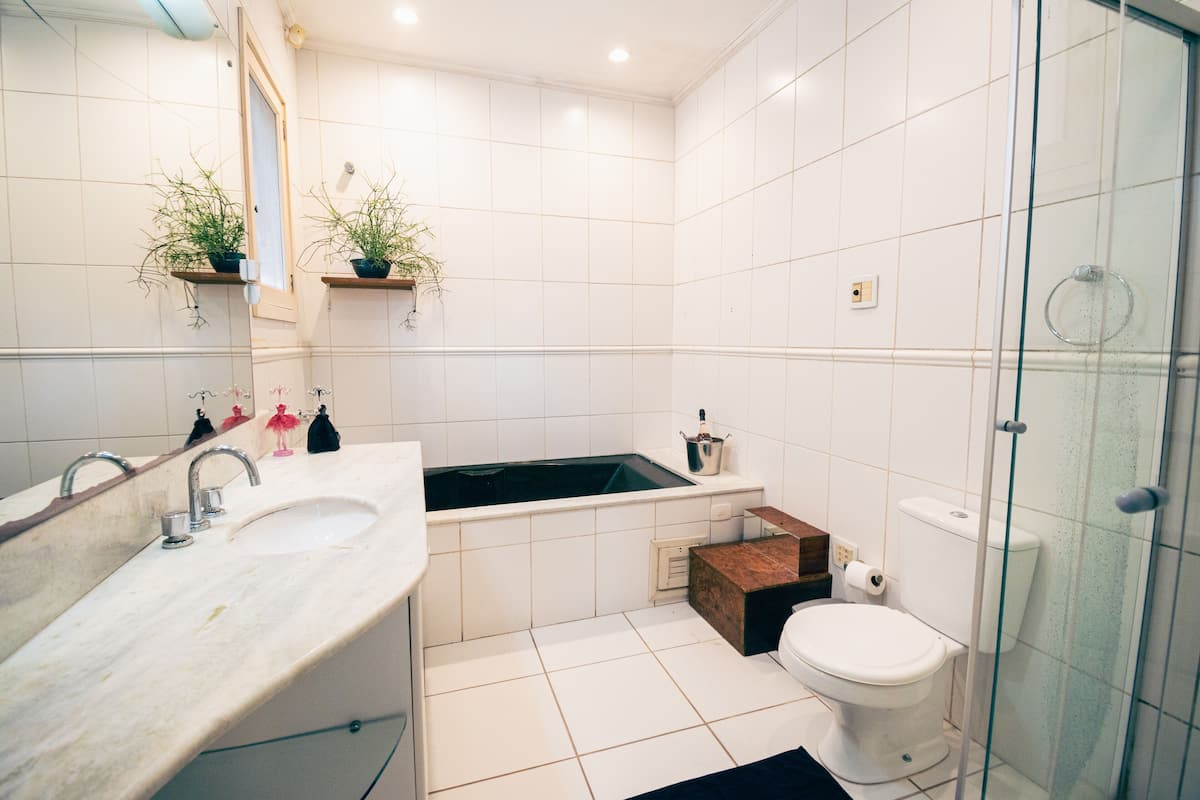 A modern bathroom with a large sink, a bathtub, a toilet, and a glass shower enclosure.