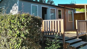Une petite cabane avec une terrasse en bois et une seule porte.