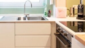Eine moderne Küche mit einer Edelstahlspüle, einem eingebauten Backofen und einer Kaffeemaschine auf der Arbeitsplatte.