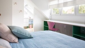 Ein Schlafzimmer mit einem Bett, einem Schreibtisch und einem Sessel.