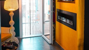 Ein modernes Wohnzimmer mit großem Fernseher, Kamin und einer Glastür, die auf einen Balkon führt.
