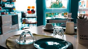 A dining table with a clear glass dome, a teal plate, and salt and pepper shakers.