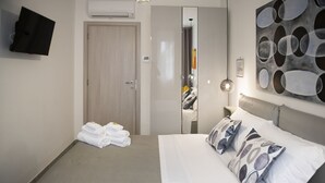 Ein Hotelzimmer mit einem Bett, einem flachbildfernseher an der Wand, einem Spiegel und einem Gemälde.