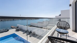 Um terraço no telhado com piscina, espreguiçadeiras e vista para o mar.