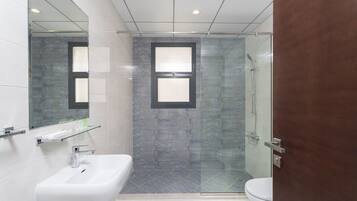 A modern bathroom with a glass shower enclosure, a white sink, and a toilet.