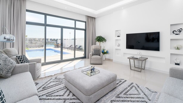 Uma sala de estar moderna com uma janela ampla, uma TV de tela plana e vista para a piscina.