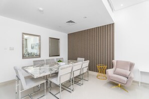 Een moderne eethoek met een marmeren tafel, transparante stoelen en een fauteuil met gouden details.