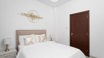 A bedroom with a bed, a nightstand, a lamp, a wall art piece, and a door.