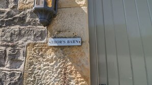 Un mur de pierre avec une plaque de rue indiquant « Thor’s Barn » et une porte sur laquelle est inscrit le numéro « 5 ».
