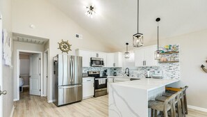 A modern kitchen with white cabinets, stainless steel appliances, and a marble island. - SeaScape Haven - Right on the sandy BEACH, Hot Tub! (Surfside Beach)