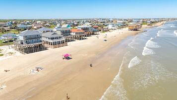 Une propriété située en bord de mer, comprenant plusieurs maisons, une jetée et une plage de sable.