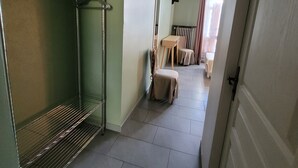 Een gang met een metalen rek, een stoel en een tafel met een tafelkleed.
