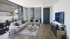 Una sala de estar moderna con un sofá modular, una mesa de centro redonda y un televisor montado en la pared.