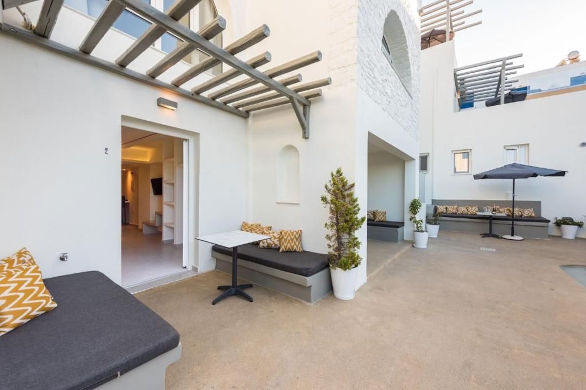 An outdoor patio area with a seating arrangement, a pergola, and potted plants.