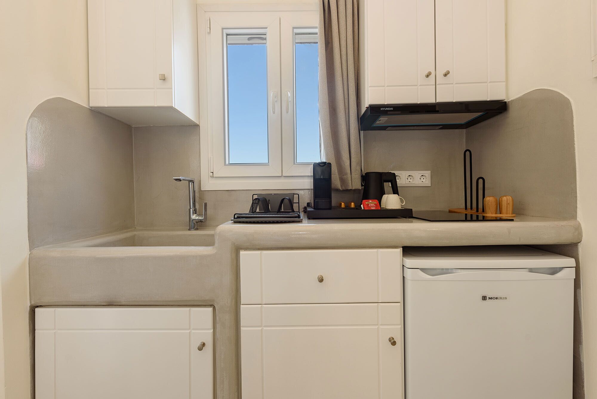A compact kitchen with a sink, a coffee maker, and a refrigerator.