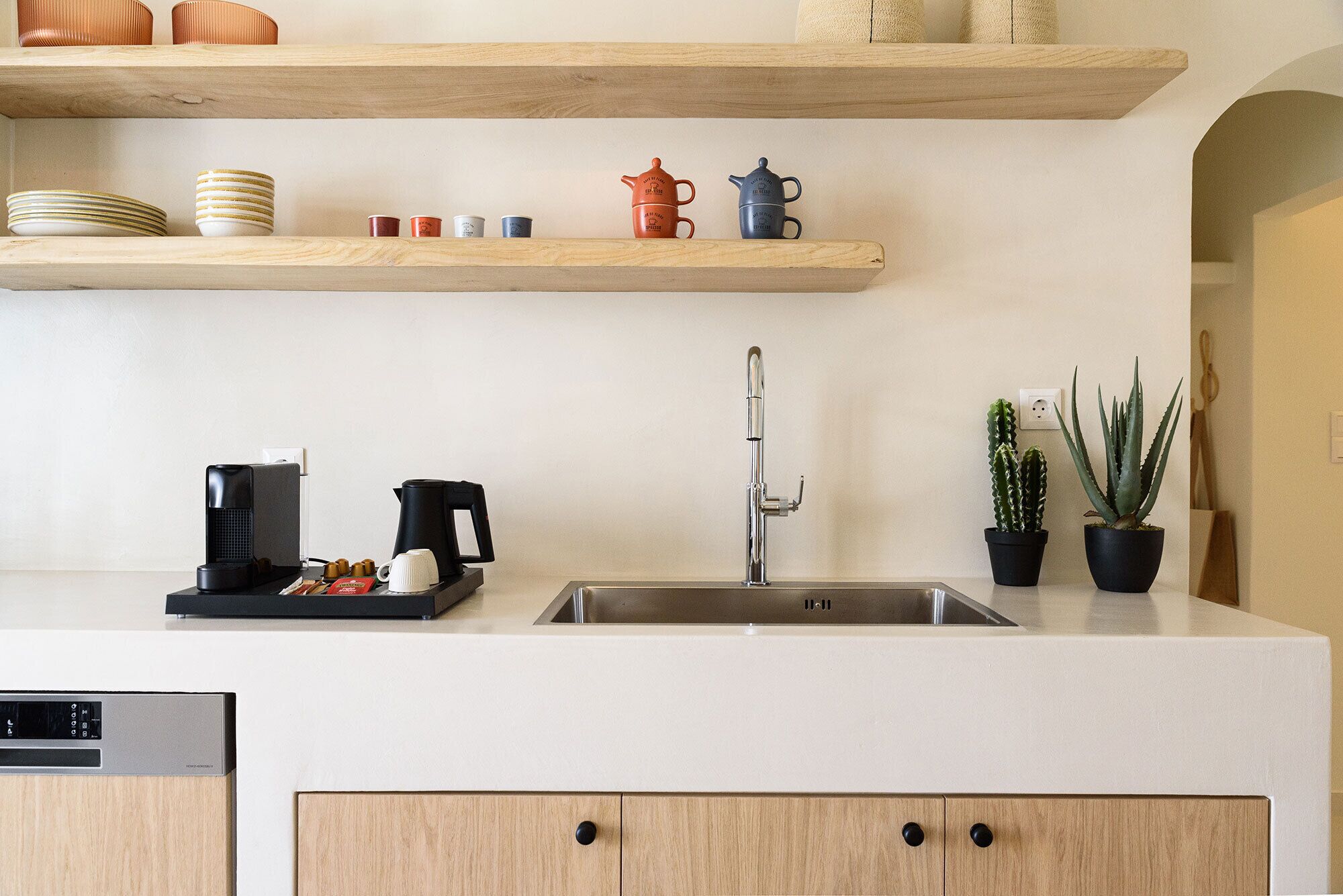 A kitchen with a stainless steel sink, wooden cabinets, and a coffee maker.