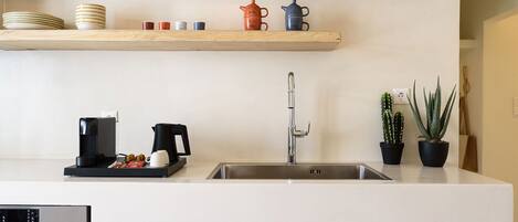 A kitchen with a stainless steel sink, wooden cabinets, and a coffee maker.