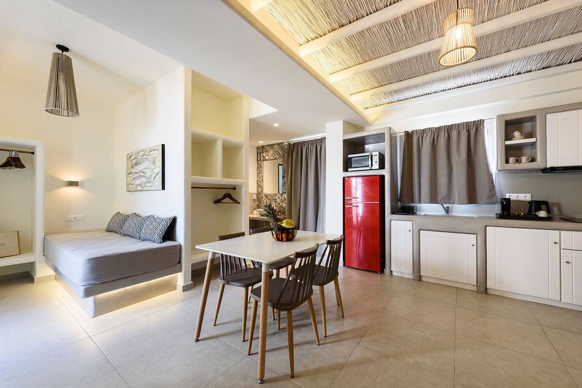 A modern apartment with a dining area, kitchen, and a living space with a sofa and a table.