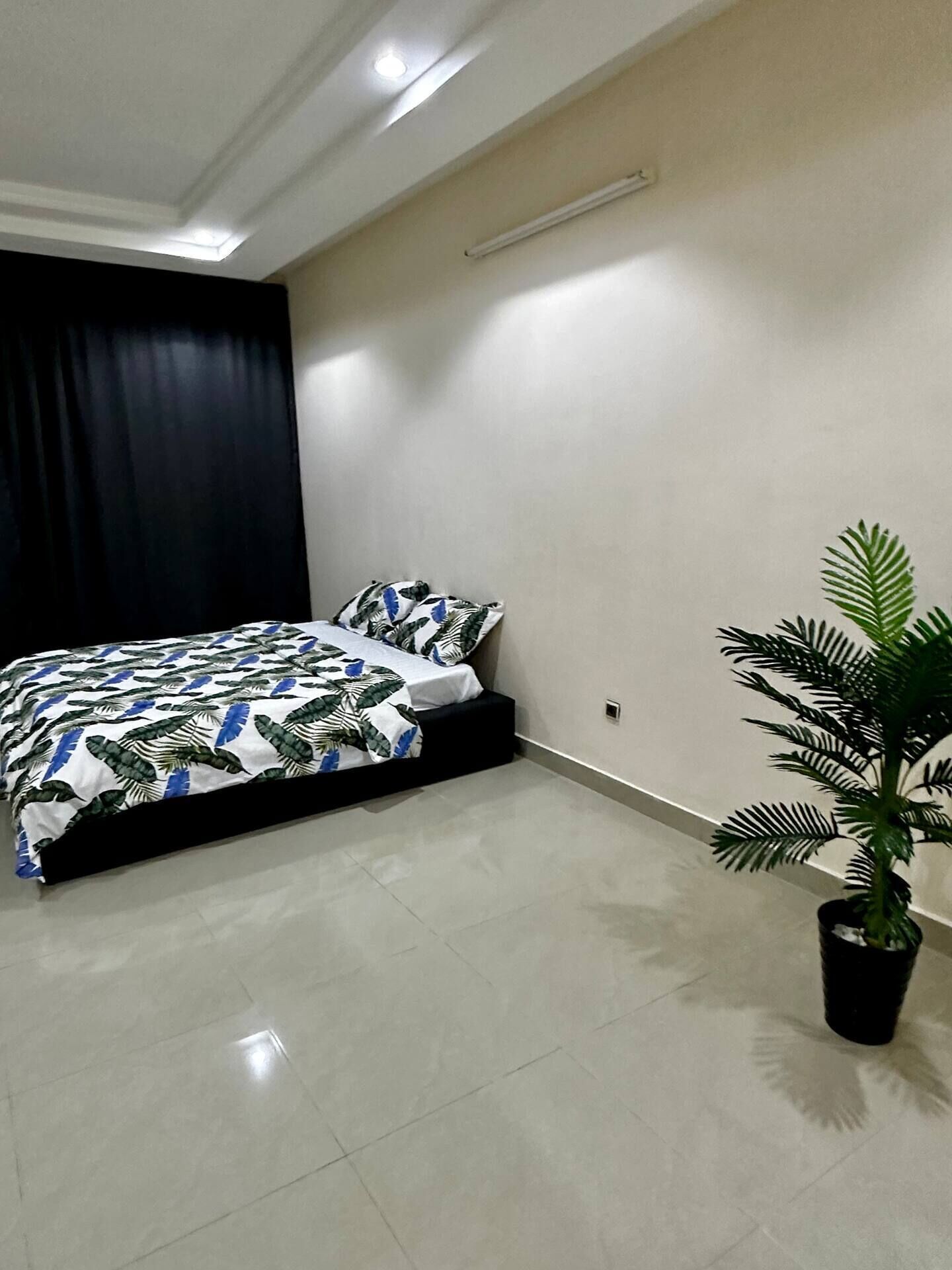 Une chambre à coucher avec un lit, une plante en pot et un luminaire fixé au plafond.